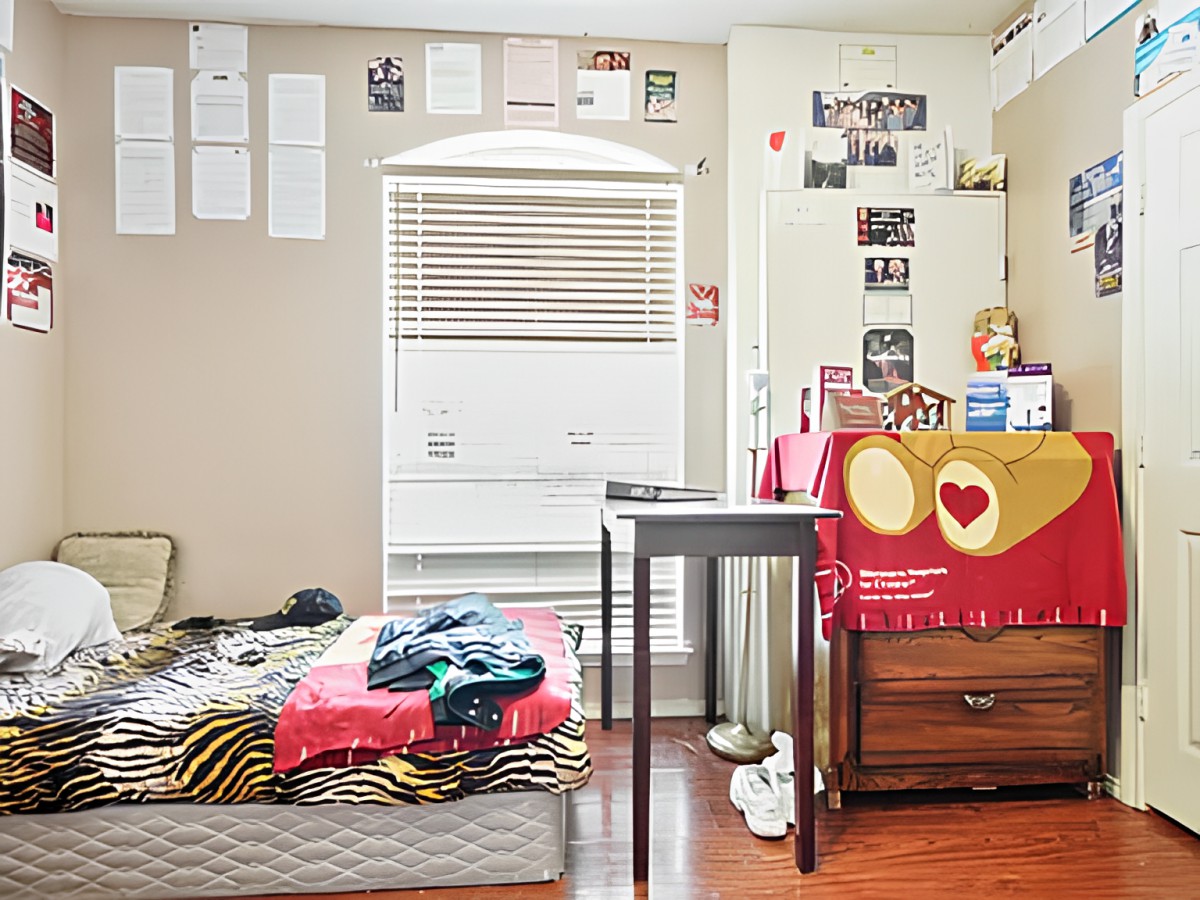 A cozy bedroom with a bed, study table, and decorative posters on the walls.