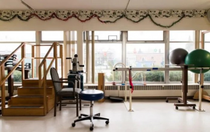 A physical therapy room with medical equipment and a large window view.