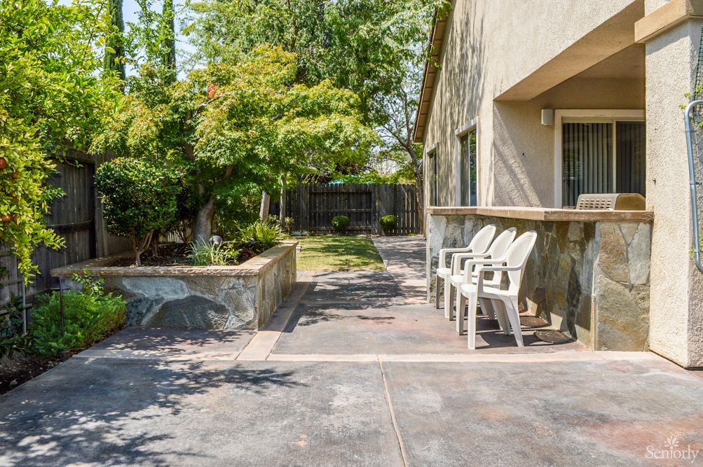 A peaceful backyard patio with chairs and lush greenery.