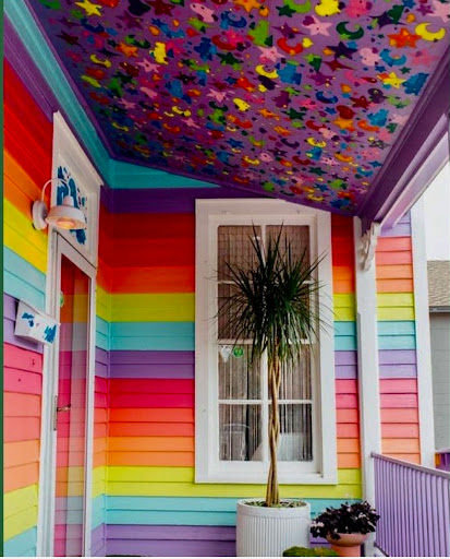 A vibrant and colorful interior showcasing a rainbow-striped wall and a beautifully painted ceiling adorned with butterflies.