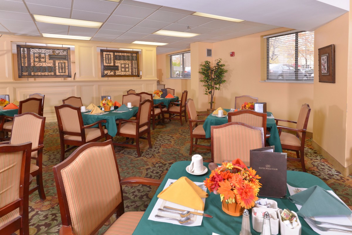 A cozy dining area with neatly arranged tables and chairs, featuring warm decor and inviting table settings.