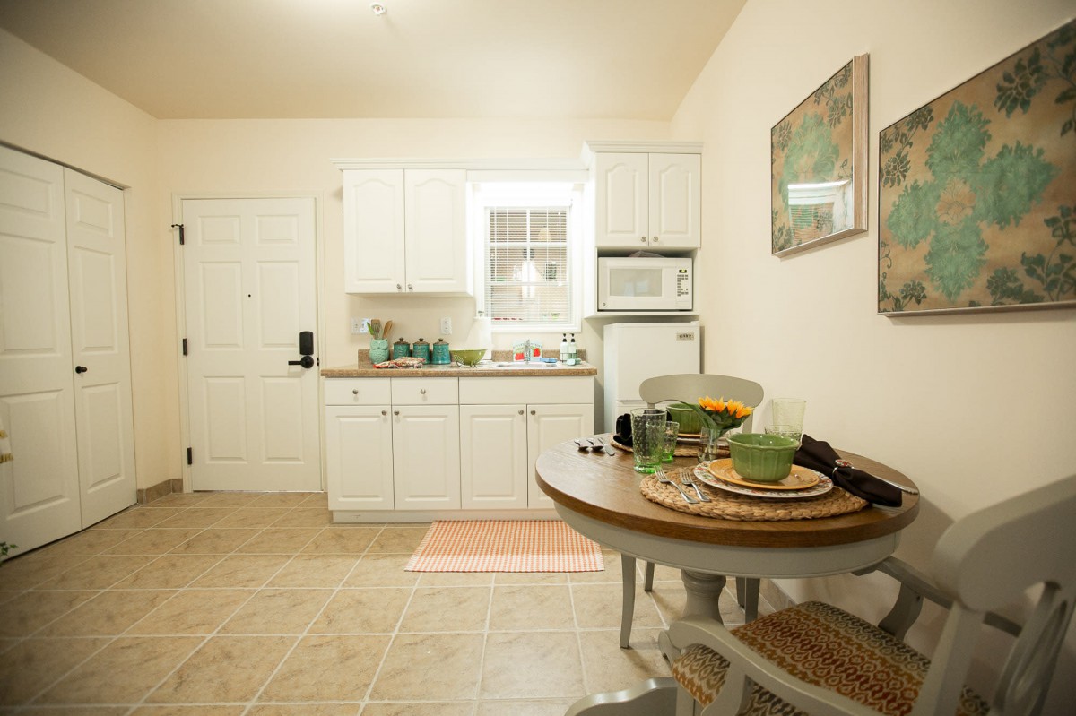 A cozy kitchen and dining area featuring white cabinets and a small table set for two.