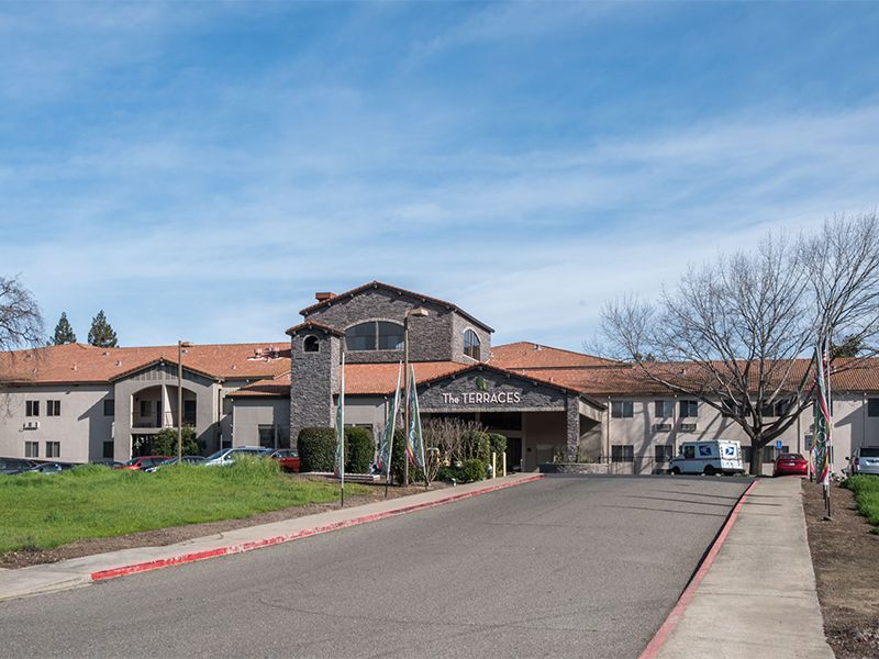 A suburban residential building with a road leading to the entrance under a clear blue sky.