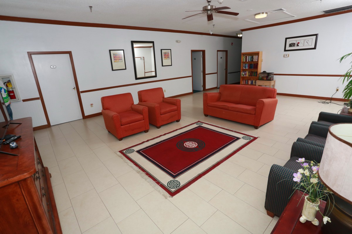 A spacious living room with red furniture and a patterned rug.