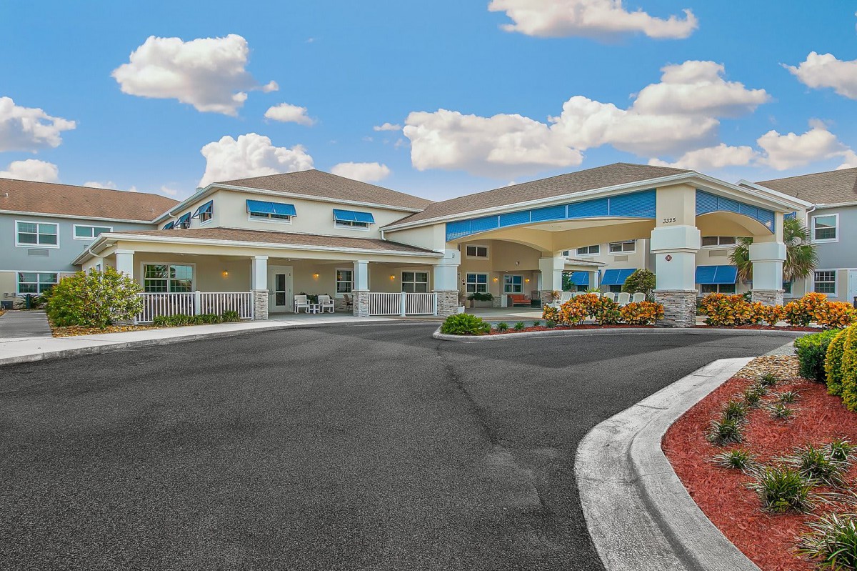 A modern building with an entrance driveway and a clear sky with clouds.