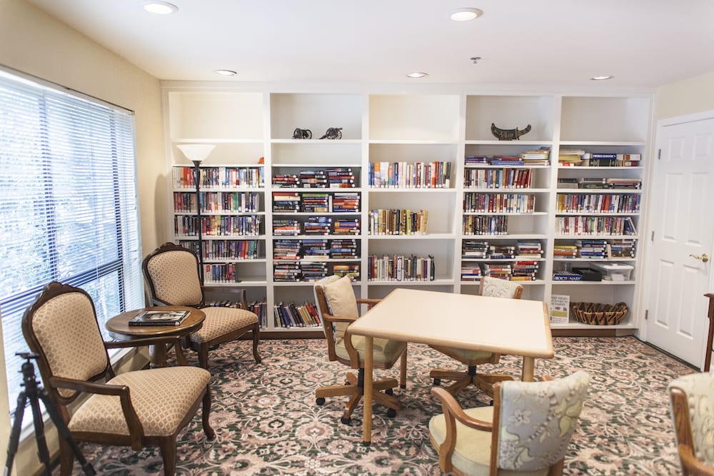 A cozy reading area with bookshelves filled with books, comfortable chairs, and a table.