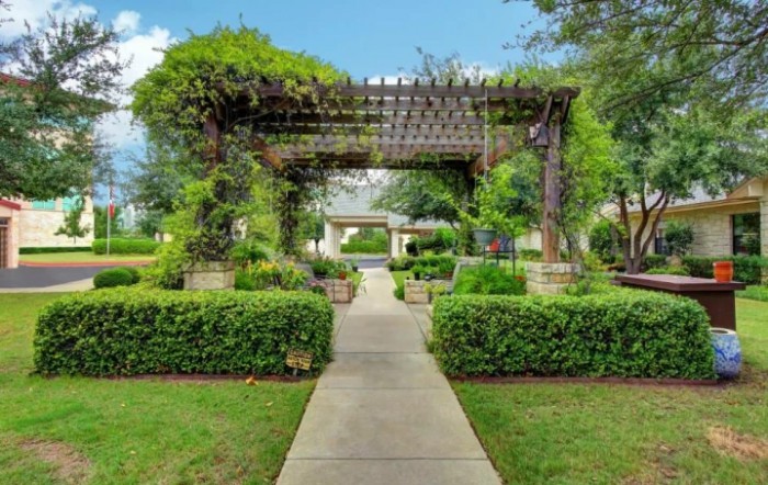 A beautiful garden with a pergola and a pathway surrounded by lush greenery.