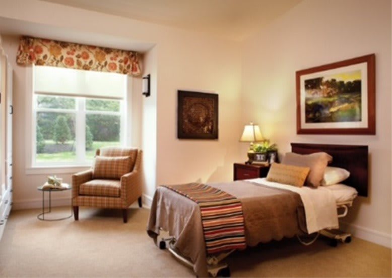 A cozy bedroom with a single bed, armchair by the window, and elegant decor.