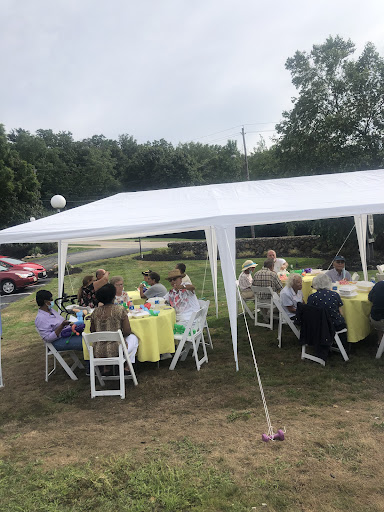 A gathering under a large white tent, with guests seated at tables for an outdoor event.
