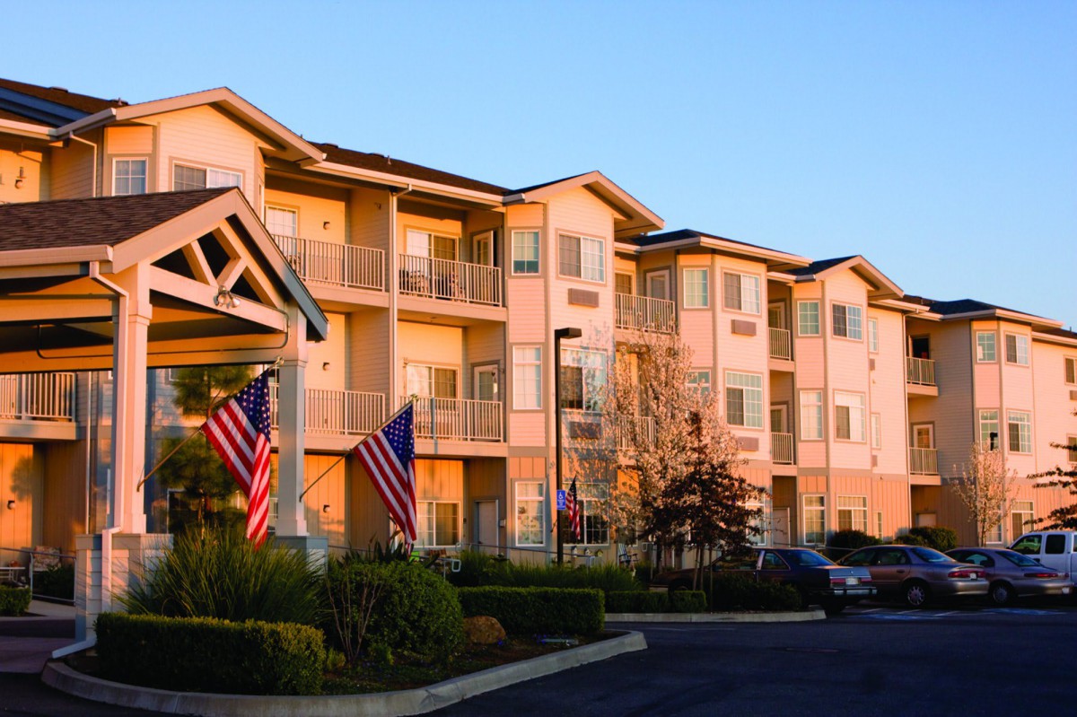 A residential apartment building adorned with flags during sunset.