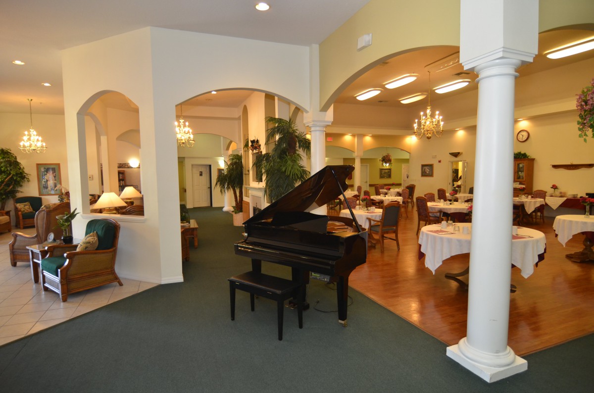 A cozy restaurant interior featuring a grand piano and elegantly set dining tables.