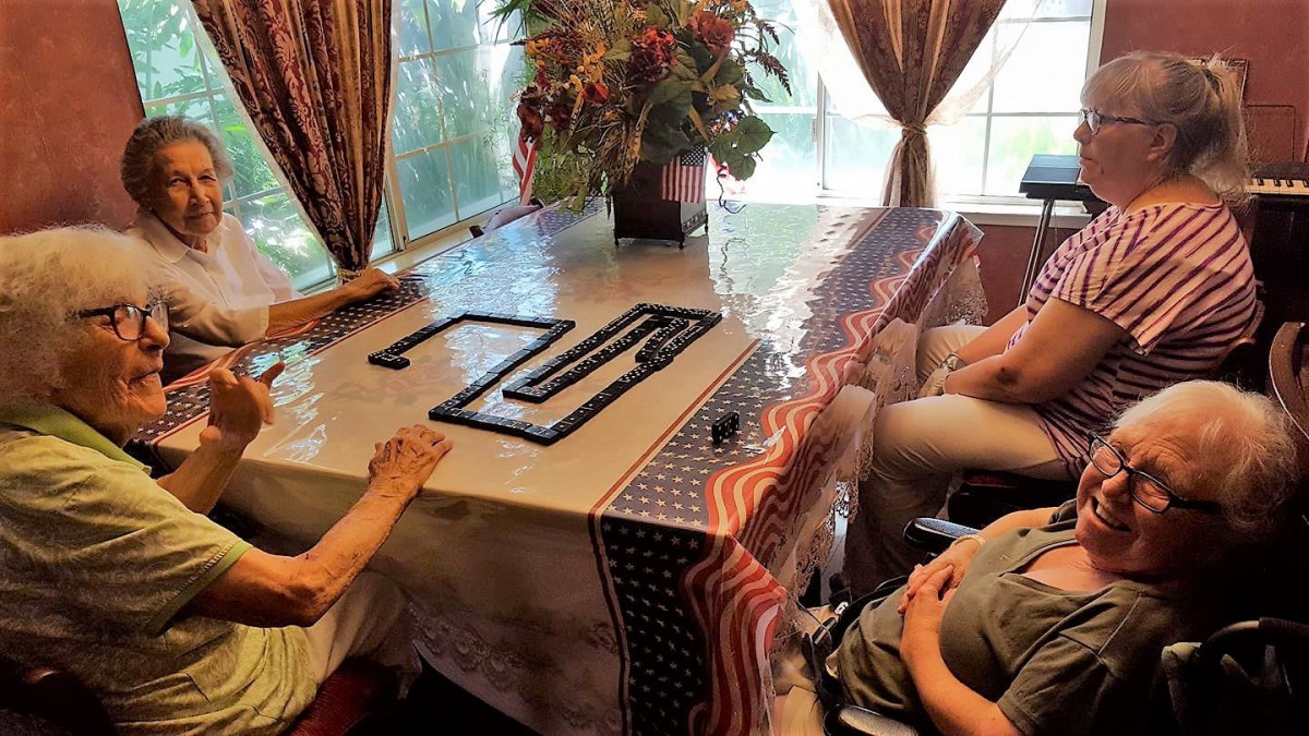 A group of people playing dominoes at a dining table.
