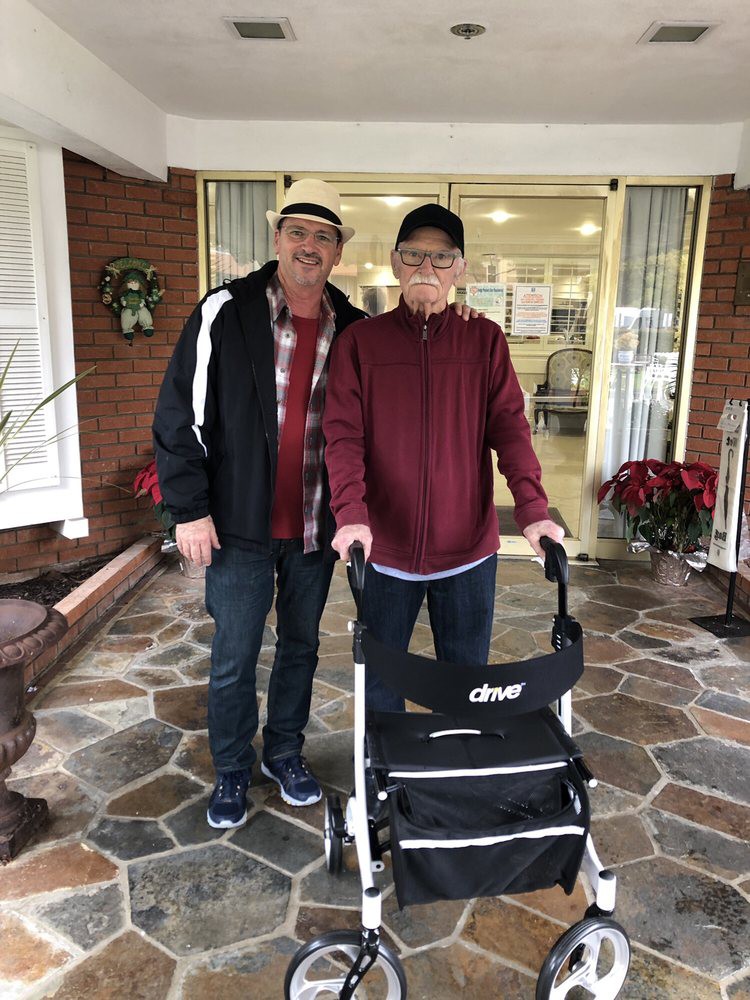 Two people standing outside a building, one using a walker.