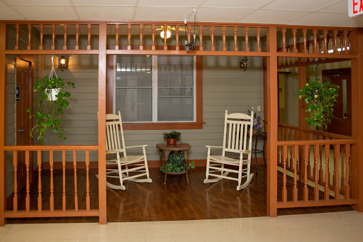 A cozy seating area featuring two rocking chairs surrounded by a wooden framework and indoor plants.