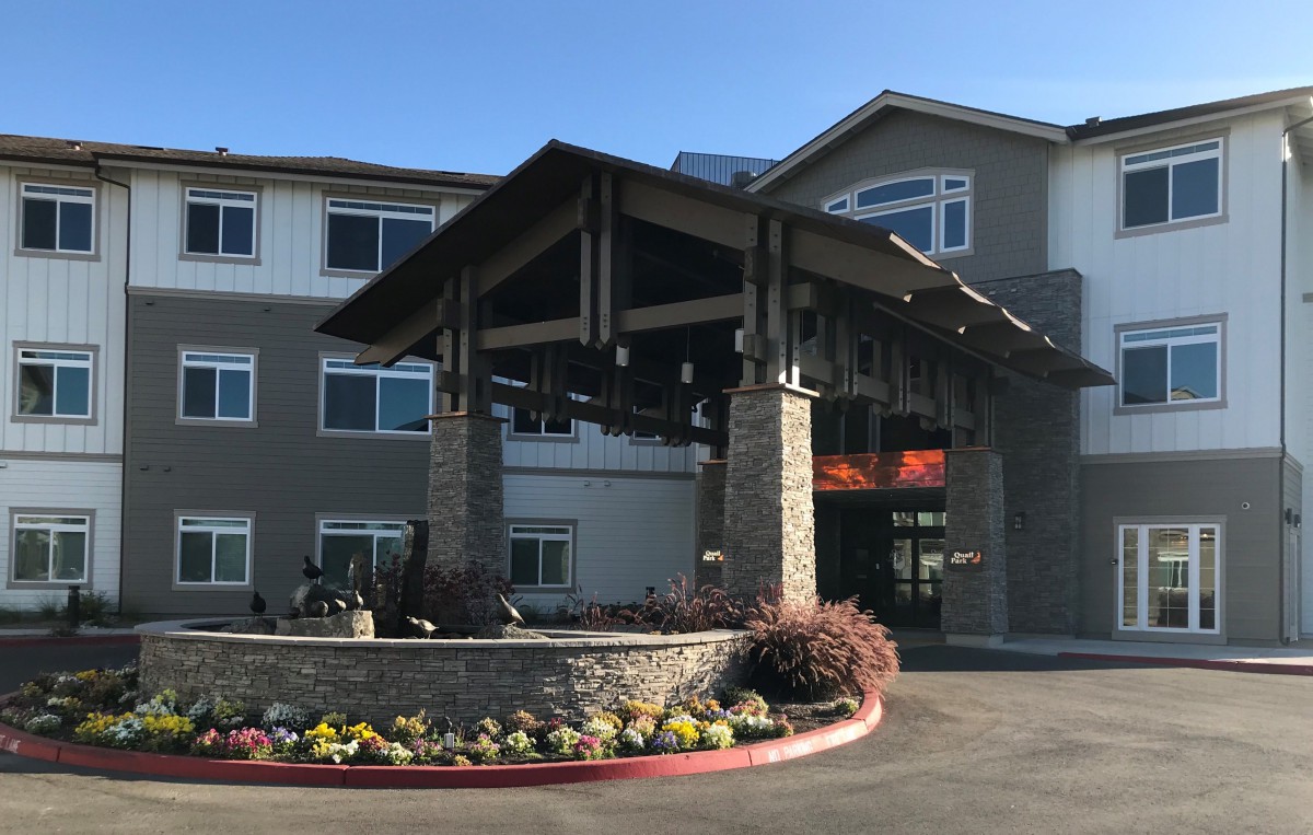 A modern building entrance with stone accents and landscaped surroundings.