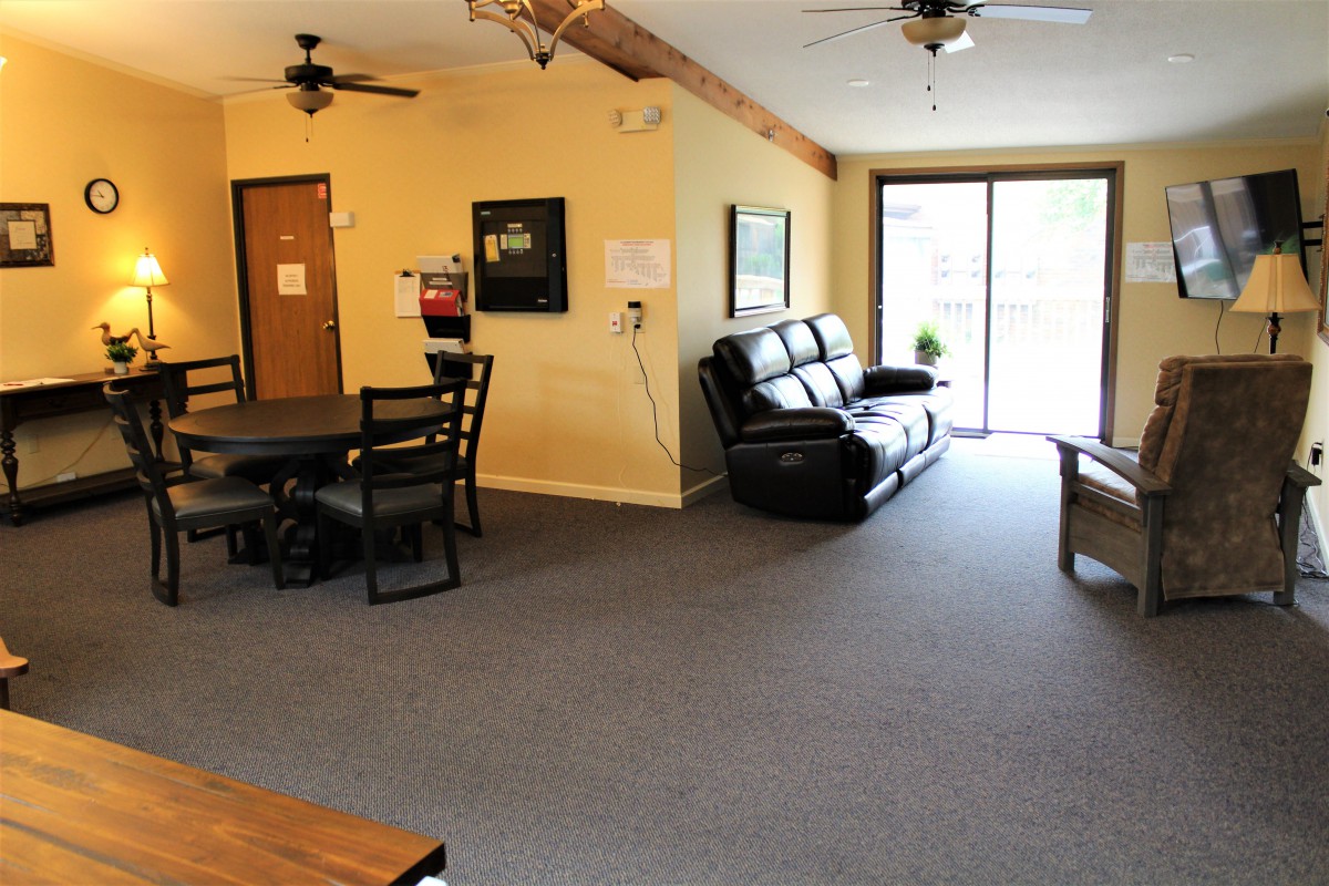A spacious living room with a sofa, dining table, and large windows.