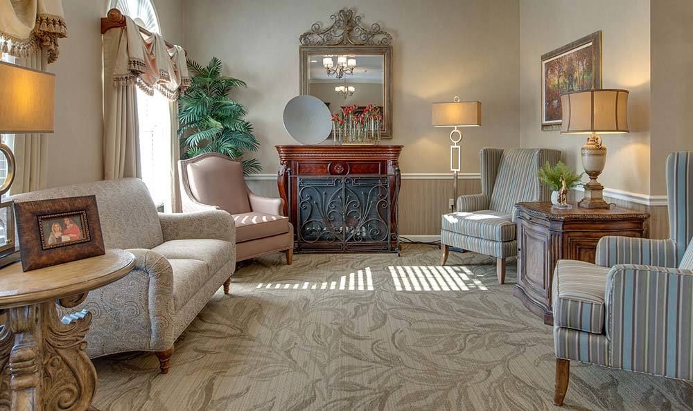 A cozy living room with armchairs, a fireplace, and decorative elements.