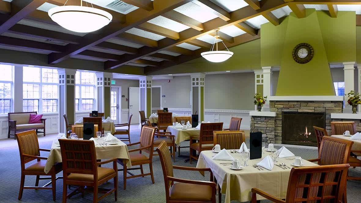 A well-decorated dining room with neatly arranged tables and chairs, featuring elegant lighting and interior design.
