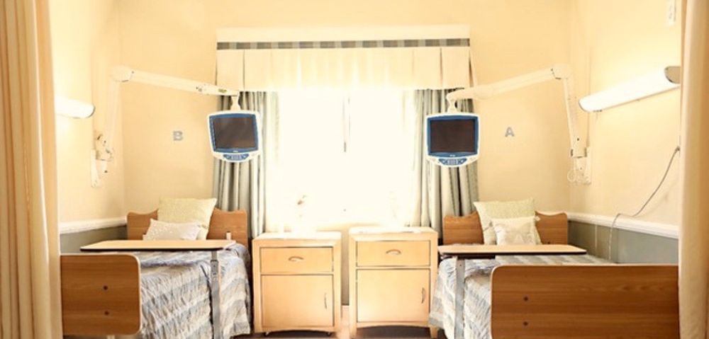 A well-lit hospital room with two beds and medical equipment.