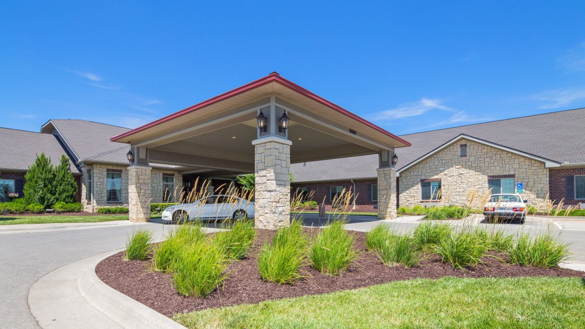 A modern building with a carport and landscaped surroundings under a clear blue sky.