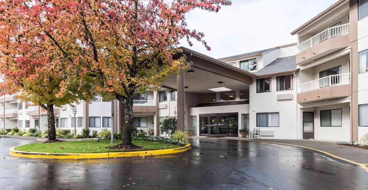 The entrance of a hotel with a circular driveway, surrounded by autumn foliage.