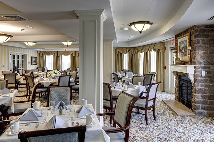 An elegant dining room with neatly arranged tables and chairs, featuring classic decor and warm lighting.