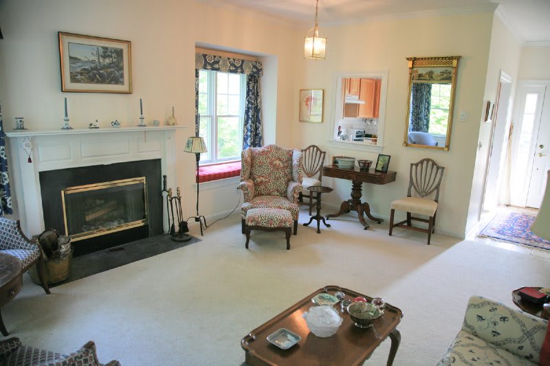 A cozy living room with traditional decor, featuring a fireplace, armchair, and coffee table.