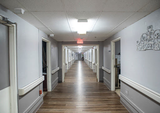 A long, well-lit hallway lined with doors on both sides.