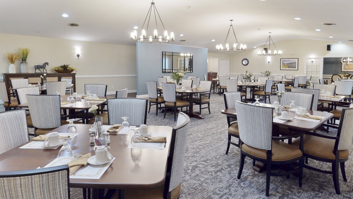 Elegant dining room with neatly arranged tables and chairs under stylish chandeliers.