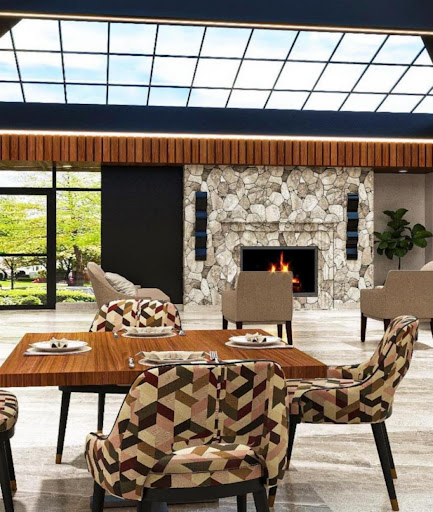 A modern interior lobby featuring stylish furniture, a cozy fireplace, and large windows that invite natural light.