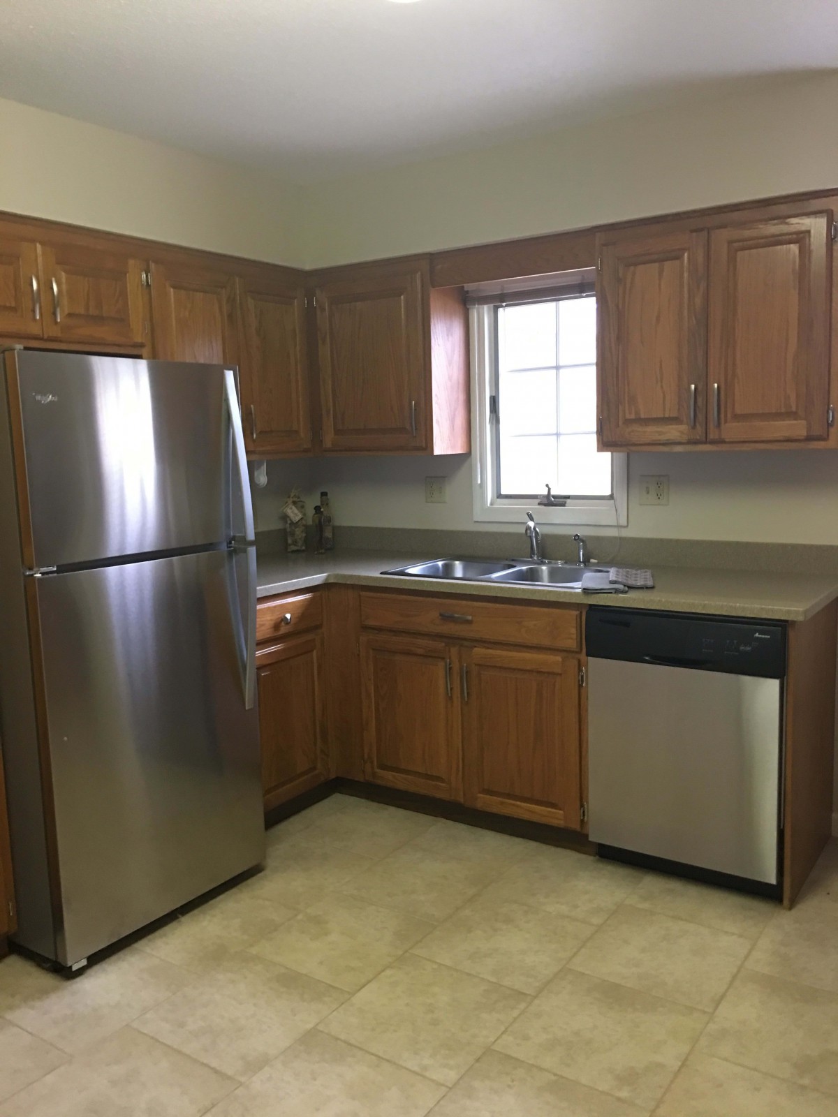 A kitchen with wooden cabinets and stainless steel appliances, including a refrigerator and dishwasher.