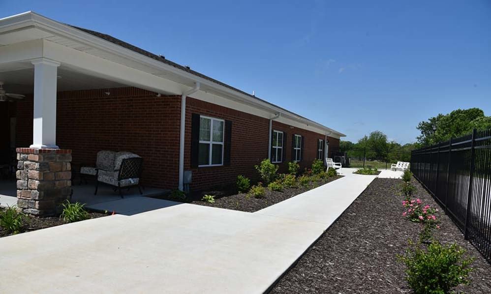 A brick building with a neatly landscaped walkway on a clear day.