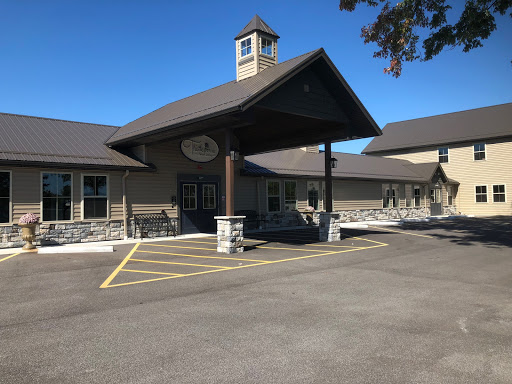 A modern building with a welcoming entrance and ample parking space, set against a clear blue sky.