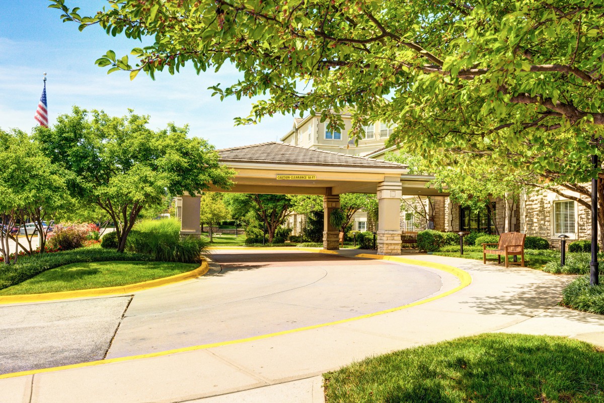 A building entrance surrounded by greenery and a curved driveway.