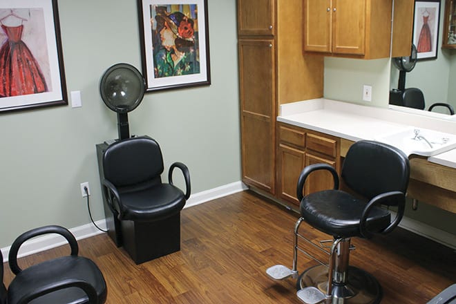 A well-organized beauty salon interior featuring chairs, a hair dryer station, and storage cabinets.