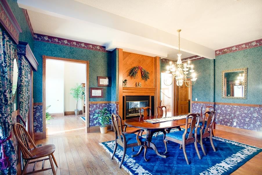 A traditional dining room with a chandelier, wooden table and chairs, a fireplace, and vibrant blue accents.