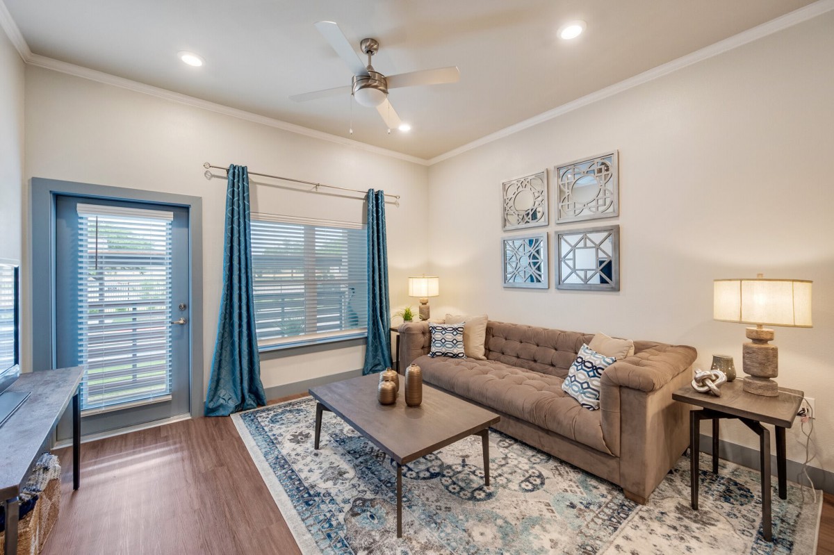 A cozy living room with a brown sofa, stylish coffee table, and blue curtains.