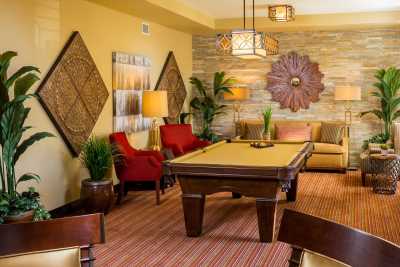 A stylish living room featuring a billiard table, red chairs, and elegant decor.