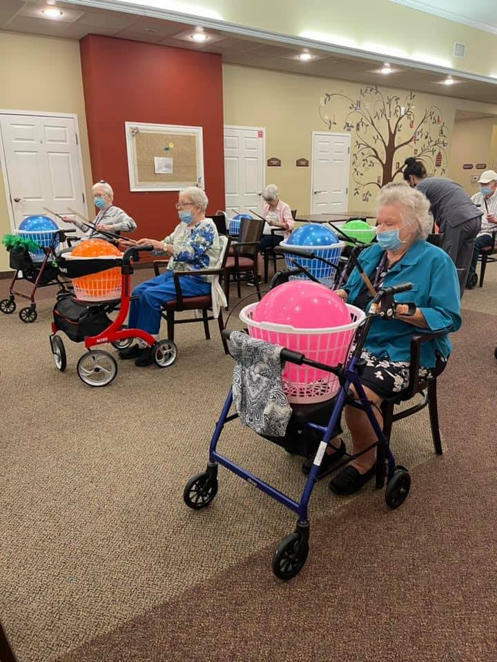 Elderly individuals in a care facility sit together with walkers and engage in knitting activities.