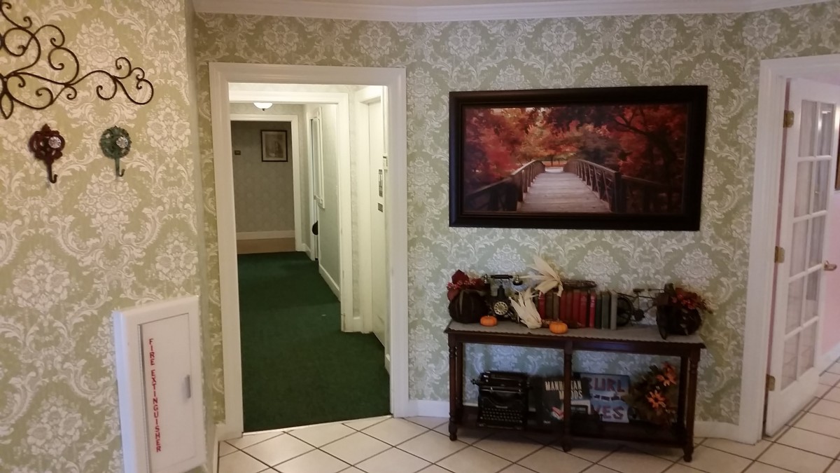 A cozy hallway with a green carpet, adorned with artwork and home decor elements.