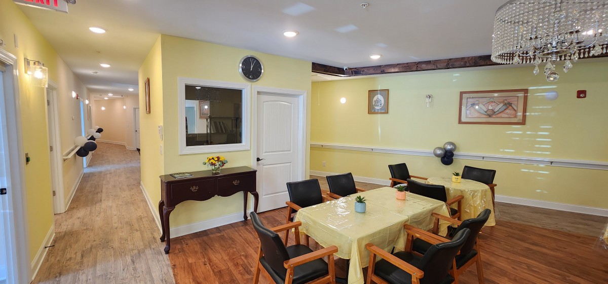A cozy dining area with yellow walls, featuring a table and chairs set, wall decor, and a clock.