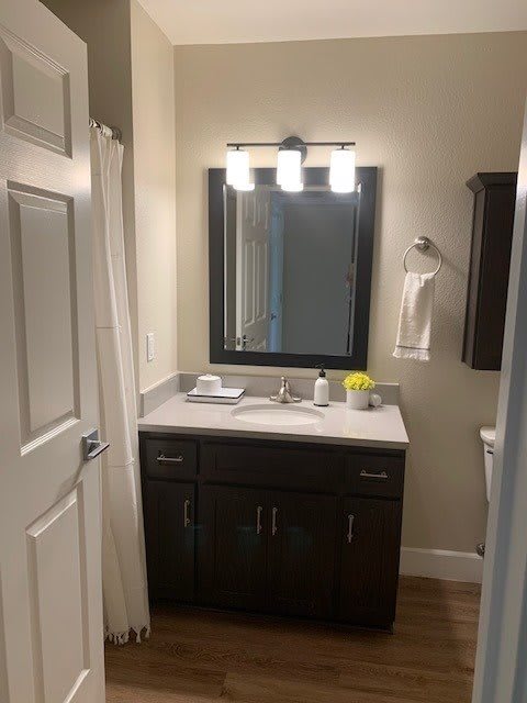 A well-lit bathroom with a dark vanity, large mirror, and towel rack.