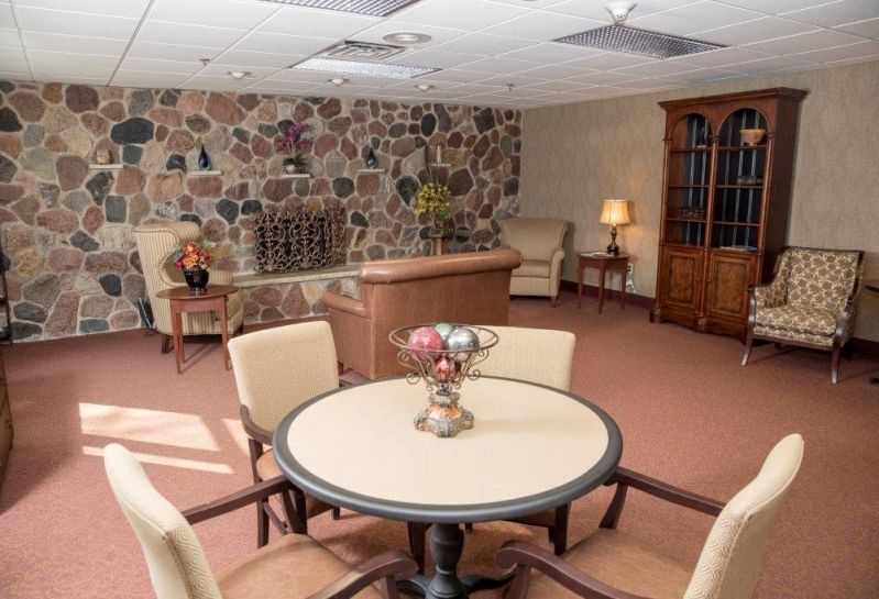 A cozy living room with a round table, chairs, and a stone accent wall.