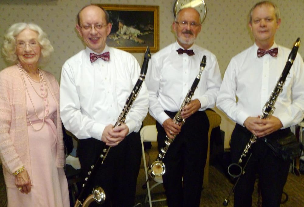 A group of musicians in formal attire holding clarinets and posing for a photo.
