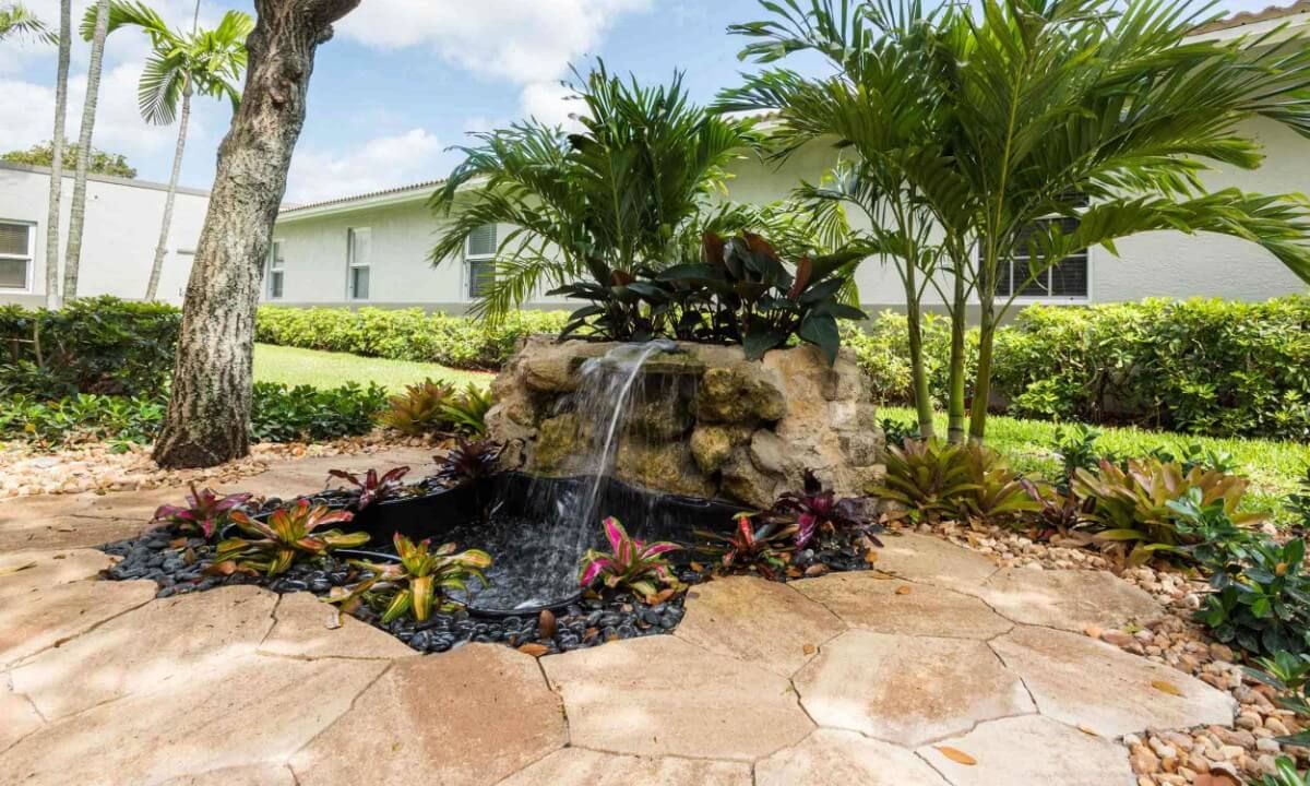 A beautifully landscaped garden featuring a small waterfall surrounded by tropical plants.