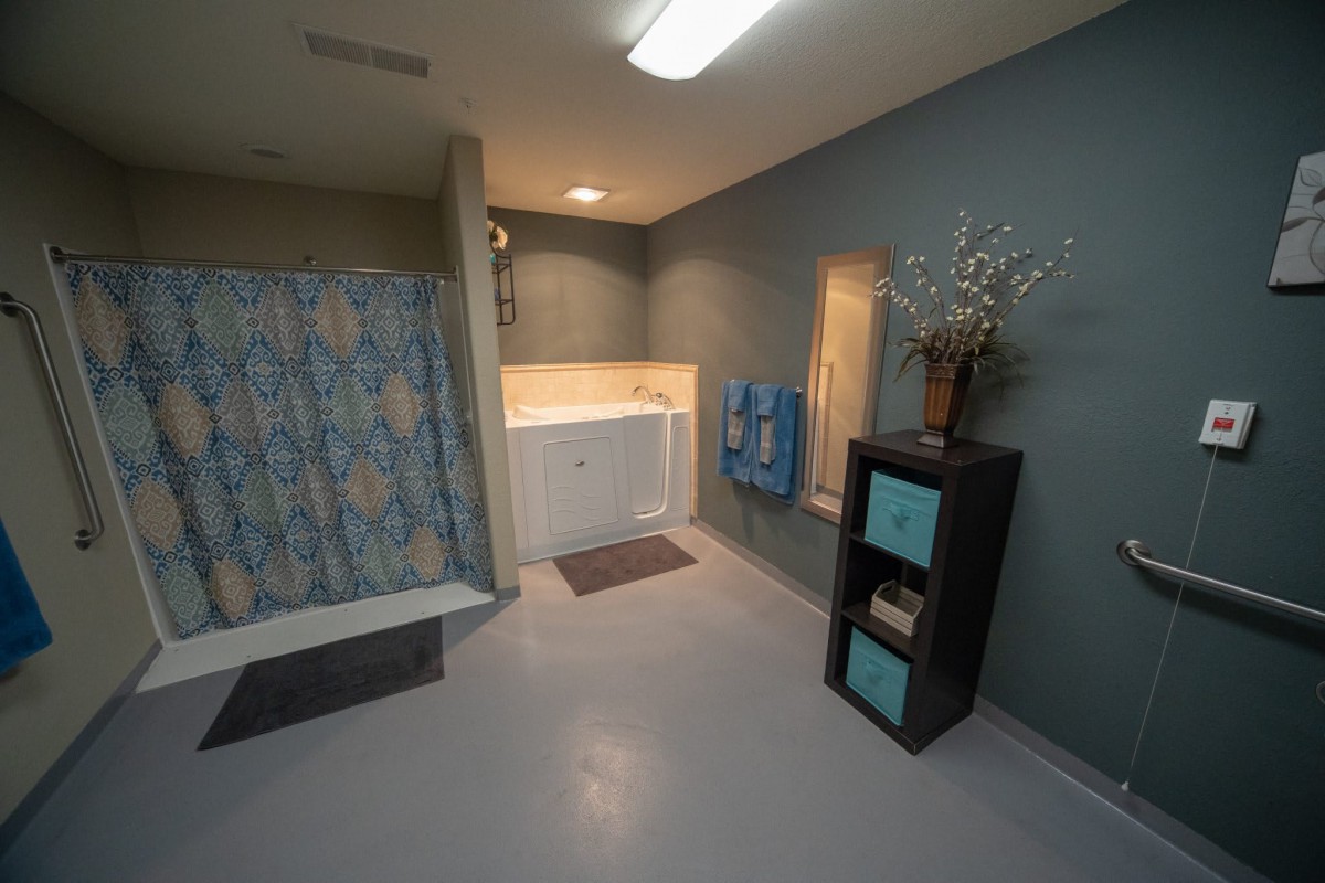 A modern bathroom with a bathtub, shower curtain, and shelving unit.