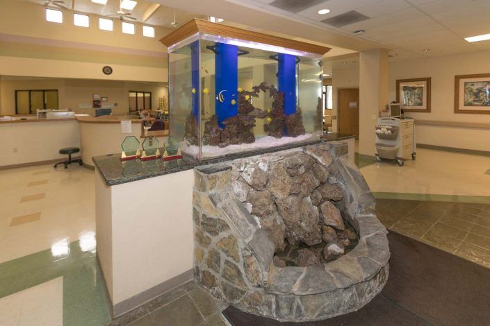 A hotel lobby featuring a large aquarium atop a rock-encased water feature.