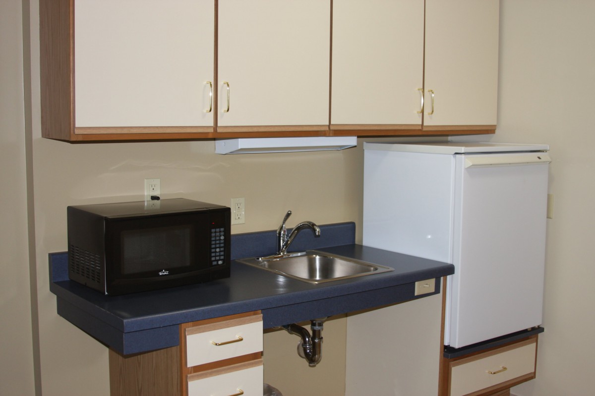 A compact kitchen area with cabinets, a microwave, sink, and refrigerator.