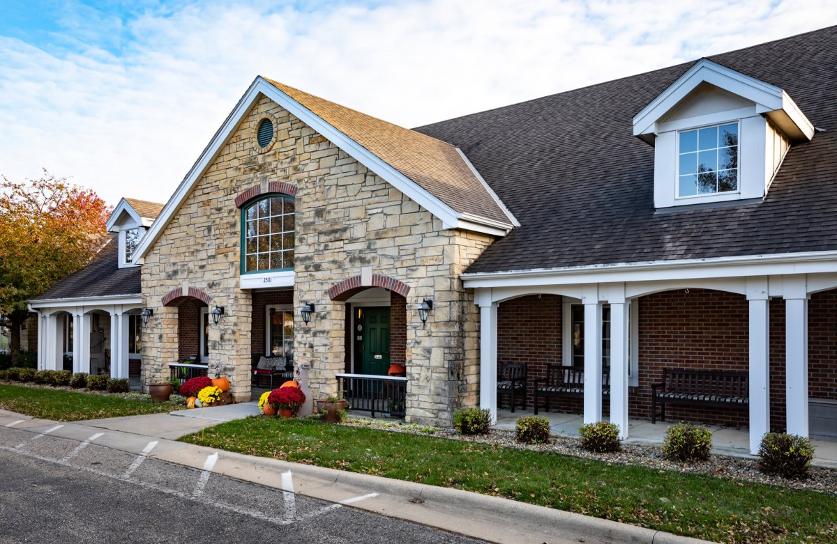 A charming residential building with a stone facade and a welcoming porch.