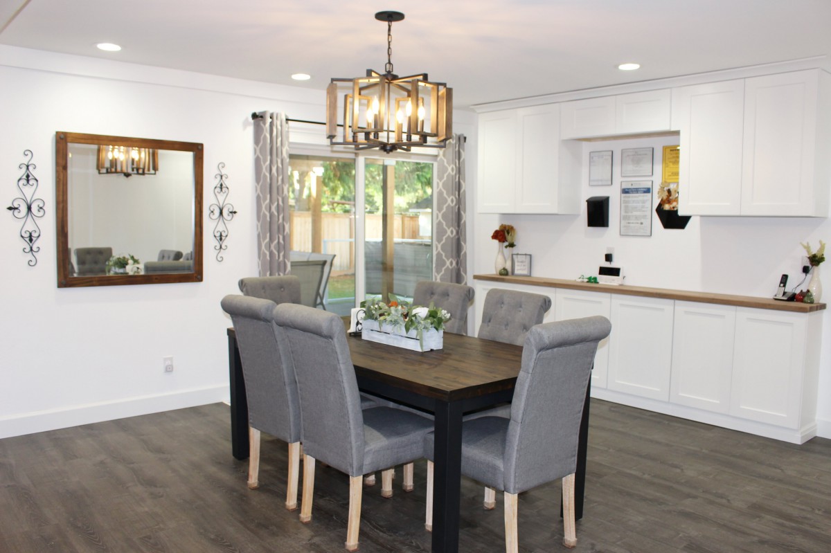 A modern dining room with a stylish chandelier and a wooden table surrounded by gray upholstered chairs.